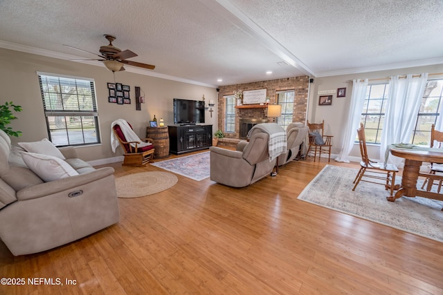 living room featuring beam ceiling, light wood-type flooring, a fireplace, and a textured ceiling