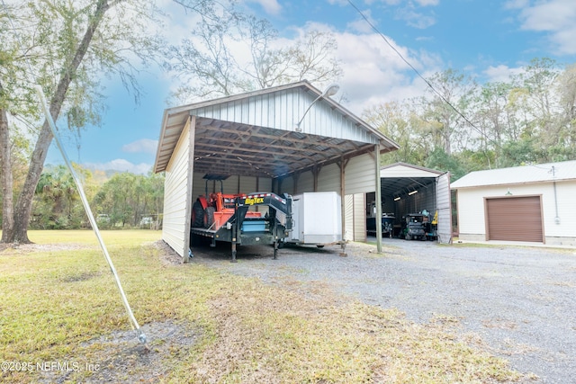 view of outdoor structure with a garage, a carport, and a yard