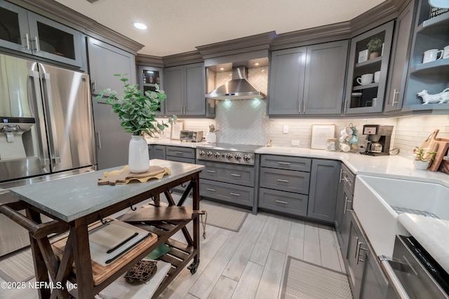 kitchen with tasteful backsplash, wall chimney range hood, gray cabinets, sink, and stainless steel appliances