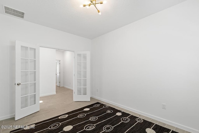 empty room with a notable chandelier and french doors