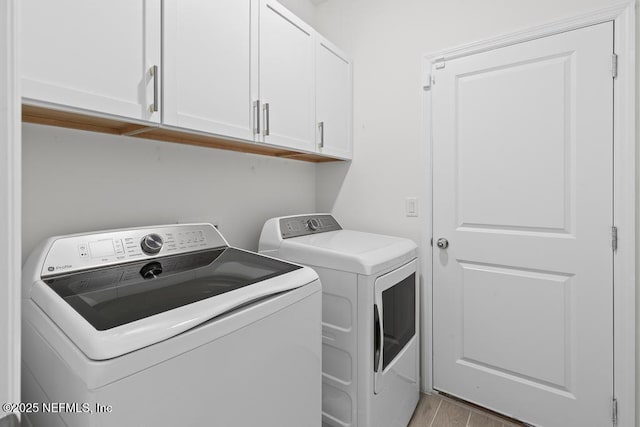 washroom with washing machine and dryer, light hardwood / wood-style floors, and cabinets