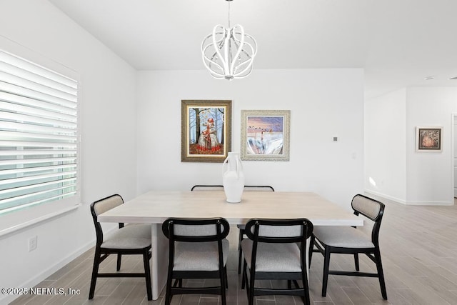 dining space with light hardwood / wood-style flooring and an inviting chandelier