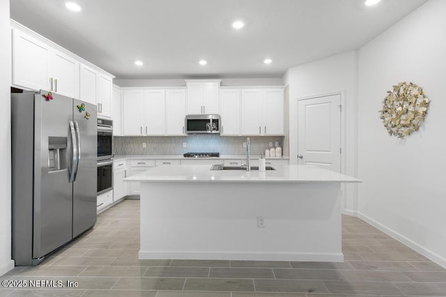 kitchen featuring an island with sink, appliances with stainless steel finishes, white cabinets, and sink