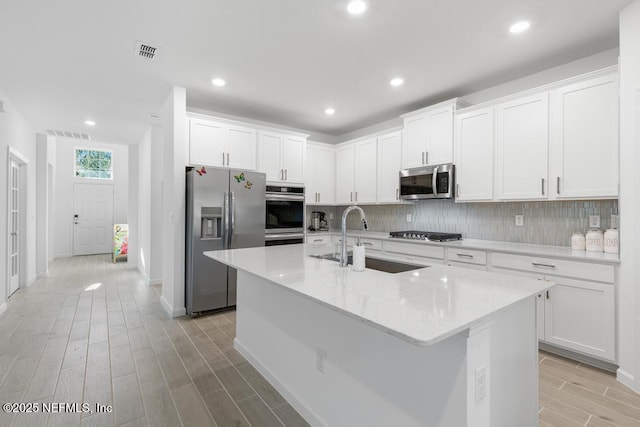 kitchen featuring stainless steel appliances, a center island with sink, white cabinetry, and sink