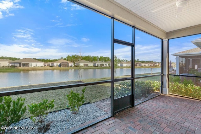 unfurnished sunroom featuring ceiling fan and a water view