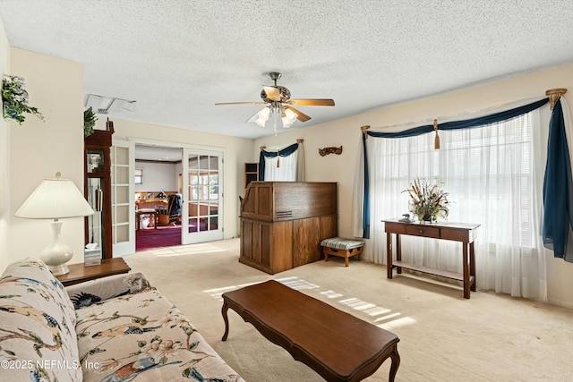 living room featuring light carpet, ceiling fan, a textured ceiling, and french doors