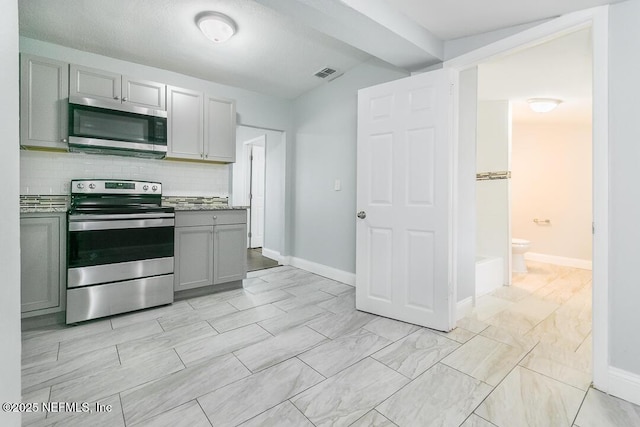 kitchen with stainless steel appliances, backsplash, and gray cabinetry