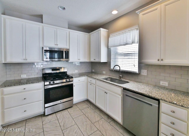 kitchen with sink, stainless steel appliances, white cabinetry, and tasteful backsplash