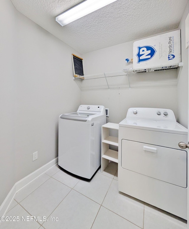 washroom featuring washing machine and dryer, a textured ceiling, and light tile patterned floors