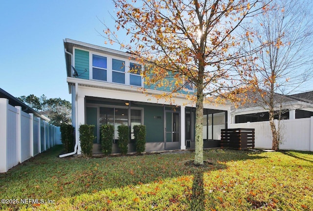 rear view of property featuring a yard and a sunroom