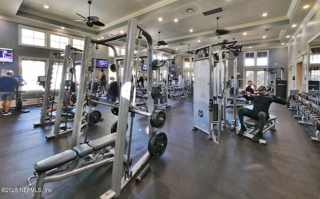 exercise room featuring a towering ceiling, a raised ceiling, and ceiling fan