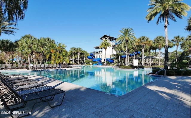 view of pool with a water slide and a patio