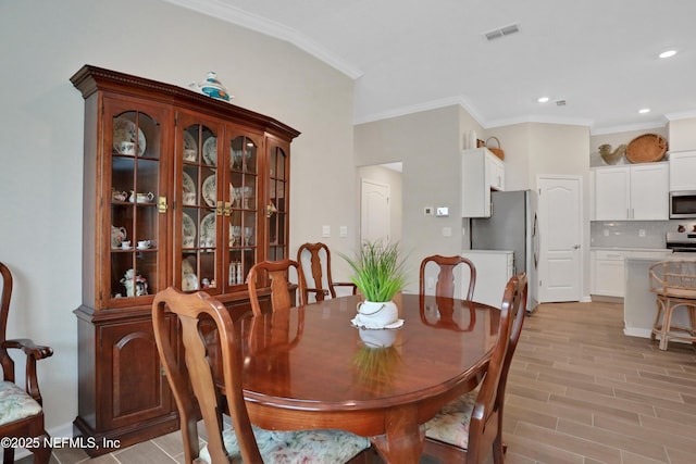 dining area with light hardwood / wood-style floors and crown molding