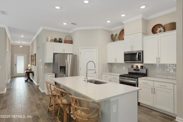 kitchen featuring white cabinetry, stainless steel appliances, a kitchen island with sink, and sink