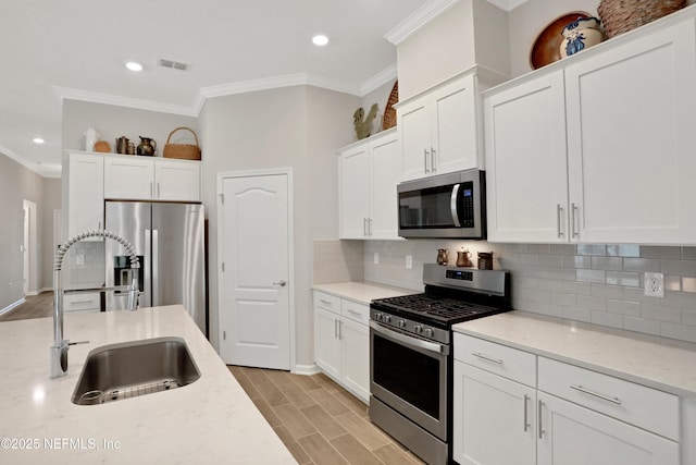 kitchen featuring sink, appliances with stainless steel finishes, white cabinets, and light stone countertops