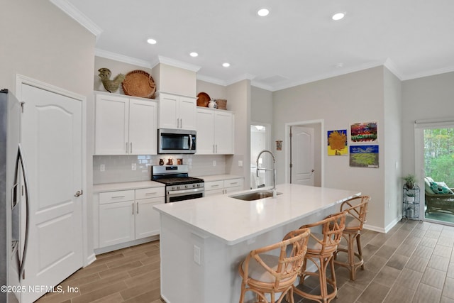 kitchen featuring appliances with stainless steel finishes, sink, an island with sink, and white cabinetry