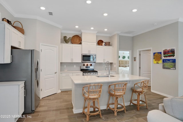 kitchen featuring white cabinetry, appliances with stainless steel finishes, and a kitchen island with sink