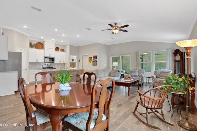 dining space with lofted ceiling, ceiling fan, ornamental molding, and sink