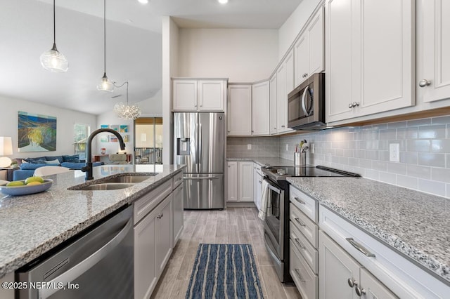 kitchen with lofted ceiling, appliances with stainless steel finishes, sink, and white cabinetry