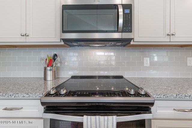 kitchen featuring stainless steel appliances, decorative backsplash, white cabinets, and light stone countertops