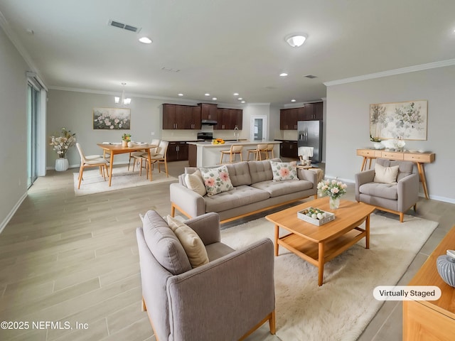 living room with light wood-type flooring, crown molding, and a chandelier