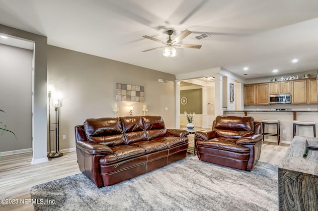 living room with ceiling fan, light wood-type flooring, and ornate columns