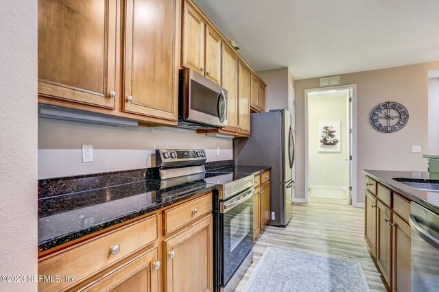 kitchen featuring sink, appliances with stainless steel finishes, dark stone countertops, and light hardwood / wood-style floors