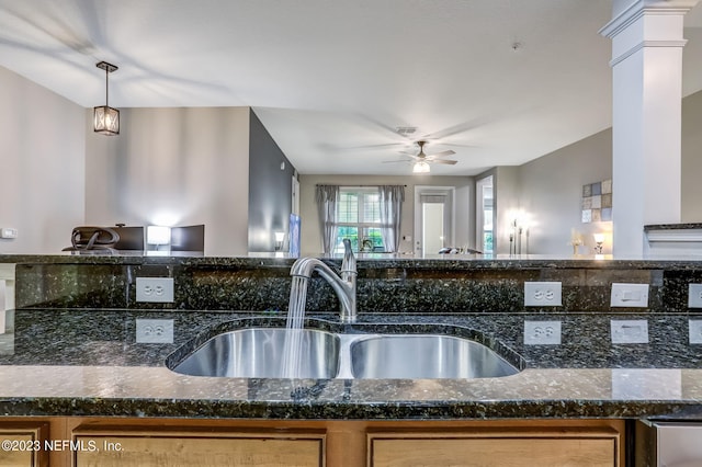 kitchen with decorative light fixtures, dark stone countertops, ceiling fan, sink, and decorative columns