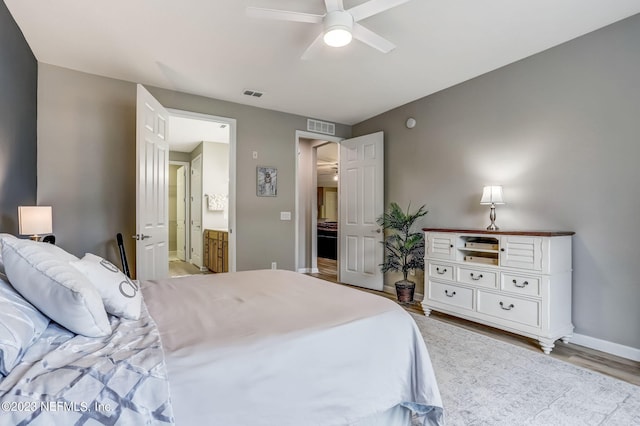 bedroom featuring ceiling fan, light hardwood / wood-style flooring, and ensuite bath