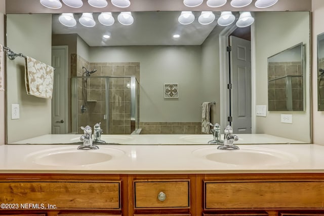 bathroom featuring a shower with door and vanity