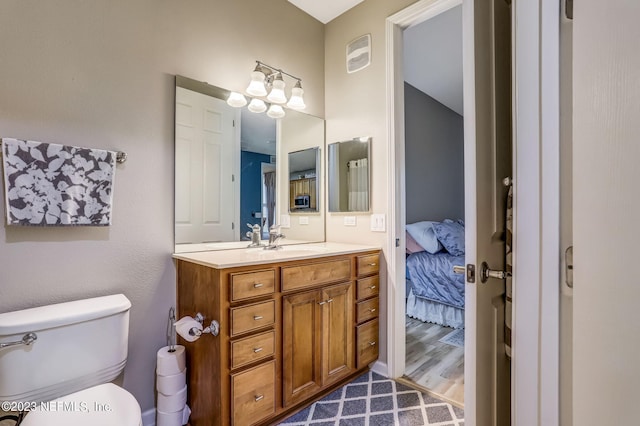 bathroom with toilet, vanity, and wood-type flooring