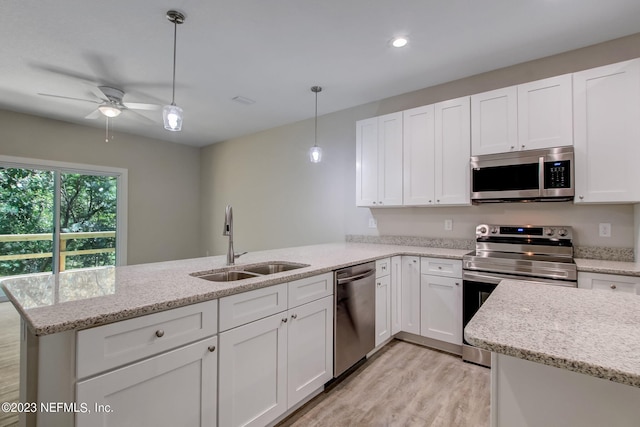 kitchen featuring stainless steel appliances, ceiling fan, sink, white cabinetry, and decorative light fixtures