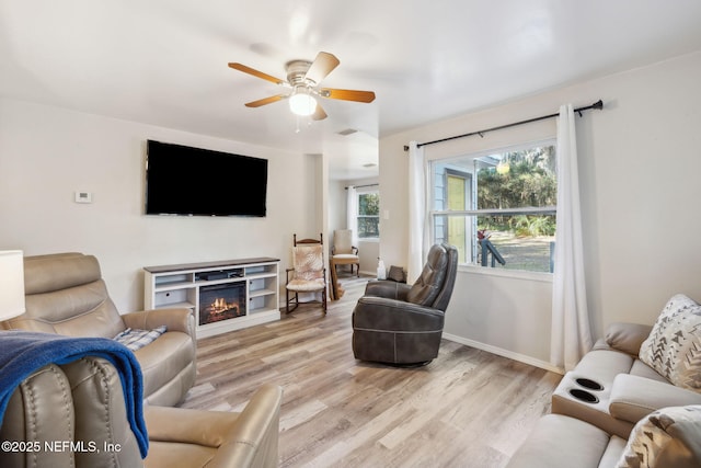 living room featuring a fireplace, light wood-type flooring, and ceiling fan