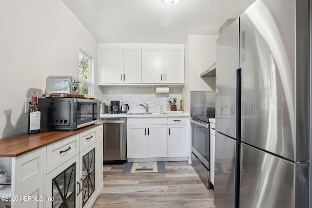 kitchen featuring appliances with stainless steel finishes, light hardwood / wood-style floors, sink, white cabinetry, and butcher block counters