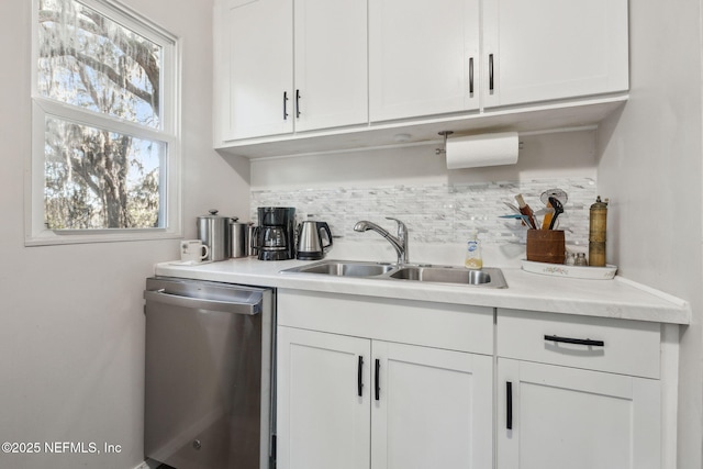 kitchen featuring stainless steel dishwasher, white cabinetry, decorative backsplash, and sink