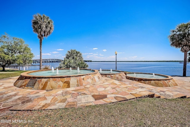 view of property's community featuring a hot tub and a water view