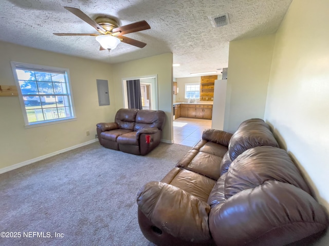 living room with a textured ceiling, ceiling fan, light carpet, and electric panel