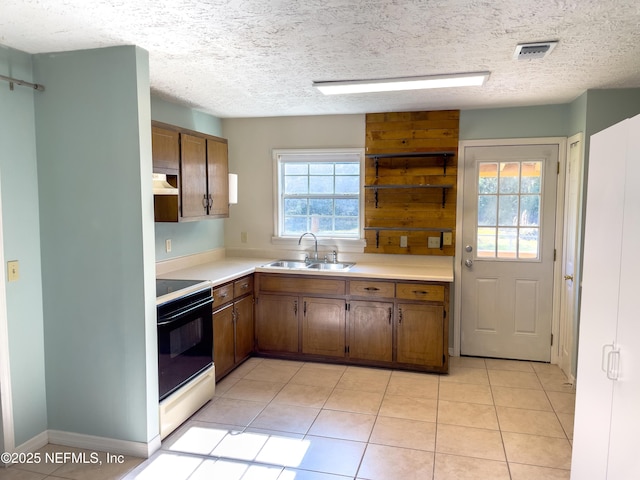 kitchen with electric range, light tile patterned flooring, sink, and a textured ceiling