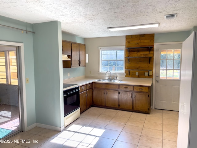 kitchen with range with electric stovetop, a textured ceiling, sink, and light tile patterned floors