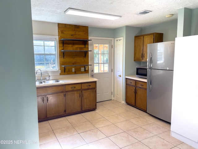 kitchen with sink, a textured ceiling, plenty of natural light, and appliances with stainless steel finishes