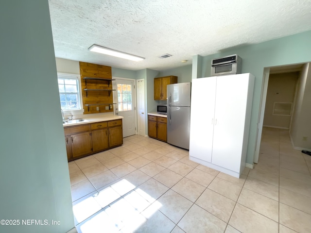 kitchen with stainless steel appliances, light tile patterned flooring, a textured ceiling, and sink