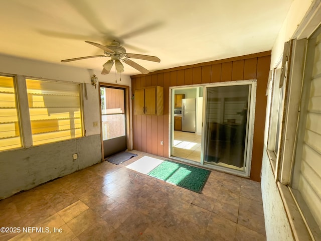 spare room with ceiling fan and wooden walls