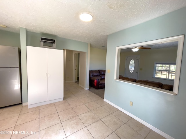 interior space with stainless steel appliances, light tile patterned flooring, a textured ceiling, and ceiling fan