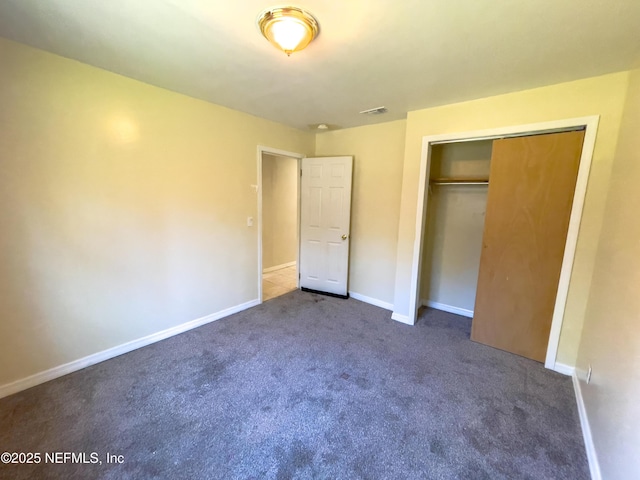 unfurnished bedroom featuring dark colored carpet and a closet