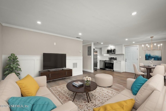 living room featuring ornamental molding, a chandelier, hardwood / wood-style flooring, and electric panel