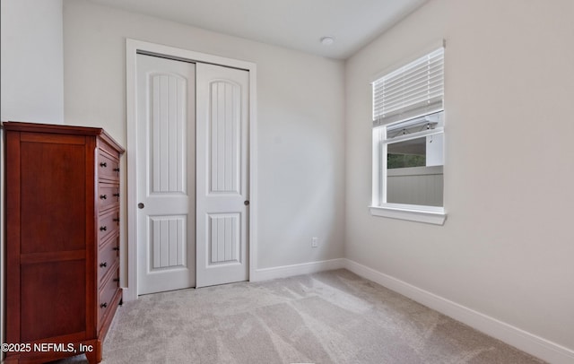 unfurnished bedroom featuring light colored carpet and a closet