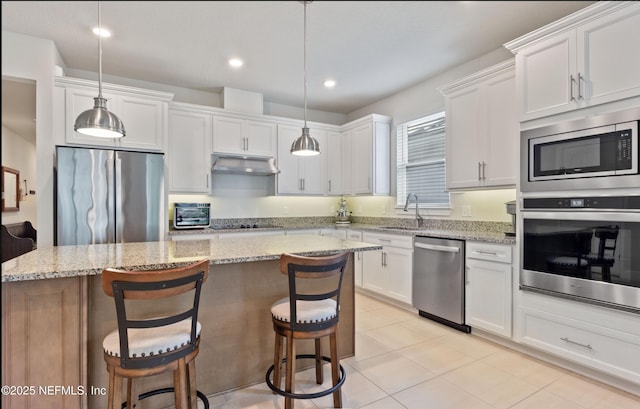 kitchen with stainless steel appliances, white cabinets, pendant lighting, and a center island