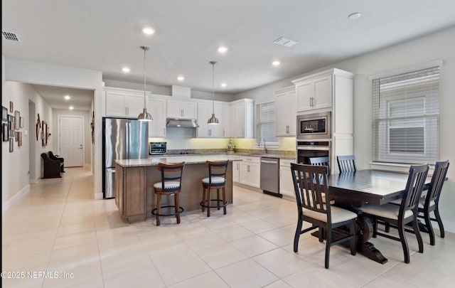 kitchen featuring stainless steel appliances, a center island, pendant lighting, and white cabinetry