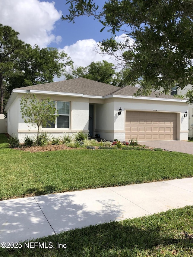 ranch-style home with a garage, stucco siding, roof with shingles, a front yard, and driveway