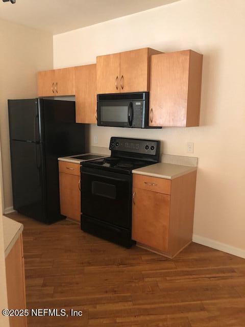 kitchen featuring dark wood-type flooring and black appliances